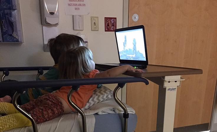 children watching tv on hospital bed